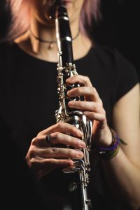 Mid-section of woman playing a clarinet in music school